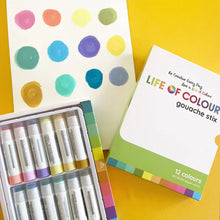 Load image into Gallery viewer, Life of Colour Pastel Gouache Paint Stix: 12 mess-free tools on a yellow surface, with a sheet displaying colored dots.
