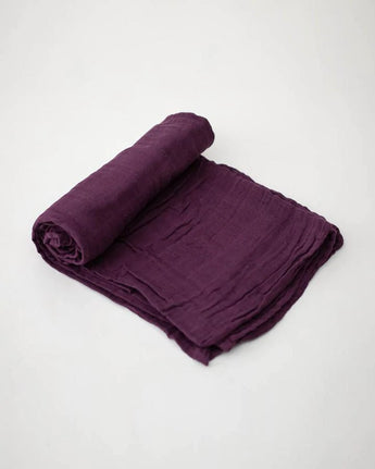 The Little Unicorn Cotton Swaddle in Plum rests on white, ready to wrap your baby in soft comfort.