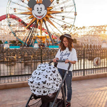 Load image into Gallery viewer, A woman in a Mickey Mouse shirt smiles, pushing a stroller with a Milk Snob Cover Disneys Mickey Sketch, near a Ferris wheel.