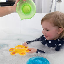 Load image into Gallery viewer, A child in a star swimsuit uses Fat Brain Toy Cos Dimpl Splash to enhance fine motor skills as water pours from a green container.