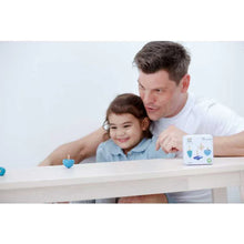 Load image into Gallery viewer, A man and child smile, enhancing fine motor skills with PlanToys sustainably made Spinning Tops at a table by a toy box.