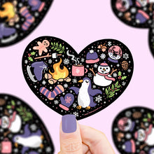 Load image into Gallery viewer, Turtle Soup Vinyl Sticker, Winter Heart: Heart-shaped with penguins, snowflakes, cocoa & mittens. Durable & waterproof on black.