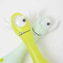 Load image into Gallery viewer, Monty the Monster and his cartoon pal, one-eyed horned figures with silly smiles, lie side by side like Sunnylife pool noodles.