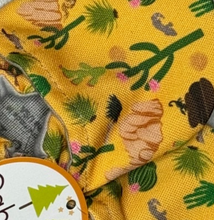 Load image into Gallery viewer, Close-up of Arizona Animals fabric by Cabooties: yellow background with green trees and brown logs, like baby shoes with elastic ankles.