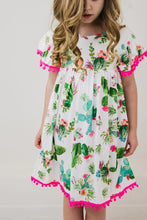 Load image into Gallery viewer, Young girl in Mila and Roses Pom Pom Dress, Cute Cactus—perfect for a playful day at the playground.