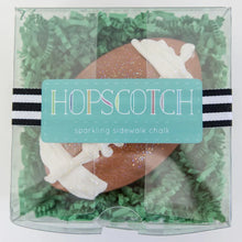 Load image into Gallery viewer, Football-shaped sparkling sidewalk chalk in a clear Hopscotch box, filled with green material, adds fun sparkles to your play.