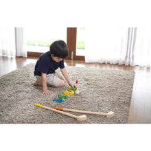 Load image into Gallery viewer, Child playing on a carpet with colorful blocks near PlanToys Mini Golf Set, wearing a navy shirt and beige shorts.