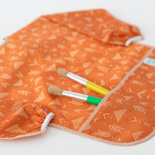 Load image into Gallery viewer, Close-up of Bumkins Long-Sleeved Art Smock: Grounded on a white background, with paintbrushes in the pocket.