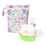 Bumkins Wet/Dry Bag: Watercolor sits near a breast pump, and a stack of cloth diapers on a white background.