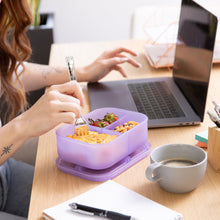 Load image into Gallery viewer, An adult eats lunch from a Bumkins Silicone Bento Box 3 Section: Purple Jelly on a desk next to a laptop, coffee cup, and notepad.