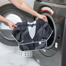 Load image into Gallery viewer, A person holds a Bumkins Sleeved Bib: Jack Skellington in front of an open washing machine.