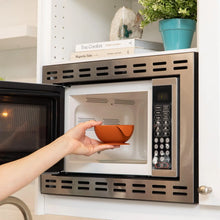 Load image into Gallery viewer, A person places a Bumkins Silicone First Feeding Set: Clay into an open microwave.