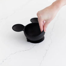 Load image into Gallery viewer, A hand lifts a Bumkins Silicone First Feeding Set: Mickey Mouse Classic Black on a marble surface, showcasing the suction cup bottom.