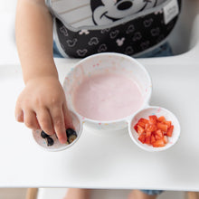 Load image into Gallery viewer, A child reaches for blueberries near yogurt and strawberries in a Bumkins Silicone First Feeding Set: Mickey Mouse Vanilla Sprinkle.