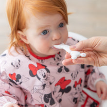 Load image into Gallery viewer, A red-haired toddler wearing a Minnie Mouse bib enjoys meal time with a Bumkins Silicone First Feeding Set: Mickey Mouse Vanilla Sprinkle.