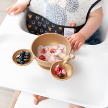 Load image into Gallery viewer, Close-up of Bumkins Silicone First Feeding Set: Minnie Mouse Gold with yogurt and berries in front of a child in a black & white bib.