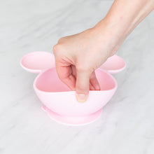 Load image into Gallery viewer, A hand holds a Bumkins Silicone First Feeding Set: Minnie Mouse Light Pink, demonstrating the suction cup bottom on a marble surface.