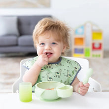 Load image into Gallery viewer, A toddler in a llama bib enjoys mealtime with Bumkins Silicone First Feeding Set: Sage; toys are in soft focus in the background.