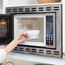 Load image into Gallery viewer, A person places a Bumkins Silicone First Feeding Set: Vanilla Sprinkle filled with food into an open microwave.