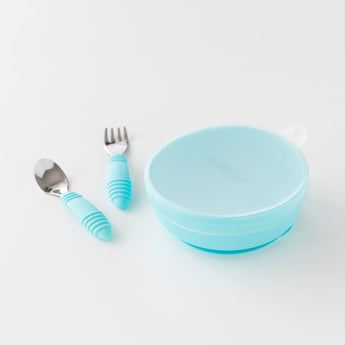 Bumkins Silicone Stretch Lid for Grip Bowl covers a blue bowl next to a blue spoon & fork set on a white background.