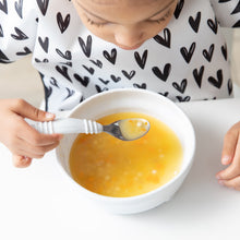 Load image into Gallery viewer, Close-up of a girl in a black & white patterned bib eating soup from a Bumkins Silicone Grip Bowl: Marble with a spoon.