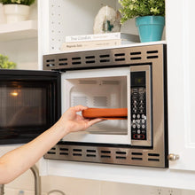 Load image into Gallery viewer, A person places a Bumkins Silicone Grip Dish: Clay inside an open microwave.