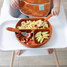 Load image into Gallery viewer, Close-up of a child in a high chair, wearing an orange bib, enjoying eggs, avocado, and fruit from Bumkins Silicone Grip Dish: Clay.
