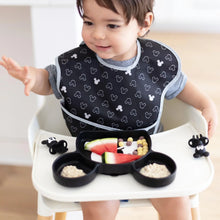 Load image into Gallery viewer, A toddler in a high chair uses Bumkins Silicone Chewtensils®: Mickey Mouse and a Mickey Mouse-shaped plate for baby-led weaning.