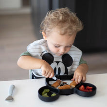 Load image into Gallery viewer, A toddler joyfully eats strawberries, grapes, and breaded food from a Bumkins Silicone Grip Dish: Mickey Mouse using a gray fork at a table.