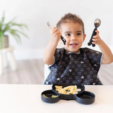 Load image into Gallery viewer, A smiling child eagerly grips a fork and spoon, ready to enjoy pasta from a Bumkins Silicone Grip Dish: Mickey Mouse at a white table.