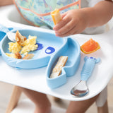 Close-up of a child in a high chair holding food over a Bumkins Silicone Grip Dish: Stitch with a matching spoon on the tray.