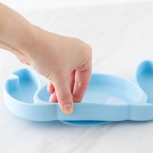 Load image into Gallery viewer, A hand holds a Bumkins Silicone Grip Dish: Stitch, demonstrating the suction cup bottom on a marble surface.