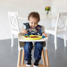 Load image into Gallery viewer, A toddler in a high chair wearing a space-themed bib eats from a Bumkins Silicone Grip Dish: Toy Story Alien with blue utensils.
