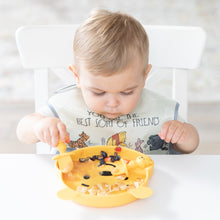 Load image into Gallery viewer, A toddler in a bib eats from a Bumkins Silicone Grip Dish: Winnie The Pooh with matching utensils at a white table.
