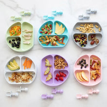 Load image into Gallery viewer, Six toddler plates, including a Bumkins Silicone Grip Dish: Gray, with snacks and matching utensils are neatly arranged on a marble surface.
