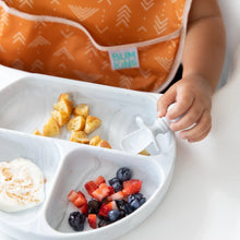 Load image into Gallery viewer, Close-up of a child in an orange bib eating pancakes, fruit, and yogurt from a Bumkins Silicone Grip Dish: Marble with a matching spoon.