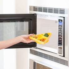 Load image into Gallery viewer, A hand places a Bumkins Silicone Grip Dish: Zelda™ Triforce, with pasta and veggies, into an open microwave.