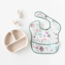 Load image into Gallery viewer, Bumkins Silicone Grip Dish: Sand sits next to matching toddler utensils and a floral bib on a white background.
