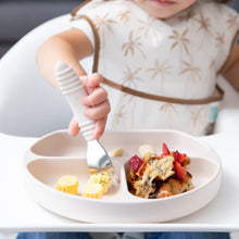 Load image into Gallery viewer, Close-up of a child in a high chair using Bumkins Spoon + Fork: Sand to eat from a matching divided plate.