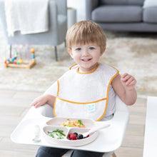 Load image into Gallery viewer, A toddler smiles in a high chair with food in Bumkins Silicone Grip Dish: Sand on the tray, next to matching utensils.