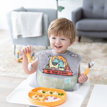 Load image into Gallery viewer, A boy in a high chair eats from a Bumkins Silicone Grip Dish: Tangerine with orange utensils, smiling while wearing a llama themed bib.