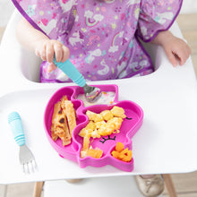 Load image into Gallery viewer, Close-up of a child in a purple patterned bib eating breakfast from a Bumkins Silicone Grip Dish Special Edition: Unicorn with blue utensils.