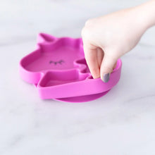 Load image into Gallery viewer, A hand holds a Bumkins Silicone Grip Dish Special Edition: Unicorn, demonstrating the suction cup bottom on a marble surface.