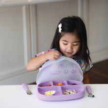 Load image into Gallery viewer, A child with long hair sits at a table, excitedly opening the lid of a Bumkins Silicone Grip Dish with Lid (5 Section): Lavender.