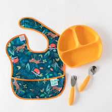Load image into Gallery viewer, A Bumkins SuperBib® 3 Pack: All Together Now lays flat on a white background next to an orange divided plate and orange utensils.