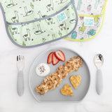 Bumkins Silicone Grip Plate: Gray with waffles, yogurt, strawberries, and granola lays near utensils and two bibs on a marble background.