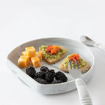 Bumkins Silicone Grip Plate: Marble with cheese, avocado toast, and blackberries with a fork and knife nearby on a white background.