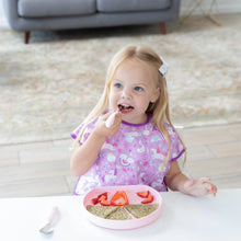 Load image into Gallery viewer, A young girl enjoys sliced fruits and toast from a Bumkins Silicone Grip Plate: Pink, wearing a purple bib with cute designs.
