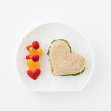 Load image into Gallery viewer, Bumkins Silicone Grip Plate: Vanilla Sprinkle holds a heart-shaped sandwich and heart-shaped pieces of fruit on a white background.