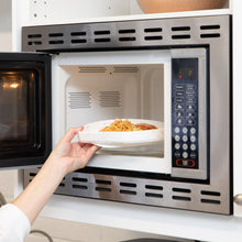 Load image into Gallery viewer, A hand placing a Bumkins Silicone Grip Plate: Vanilla Sprinkle with pasta into an open microwave.